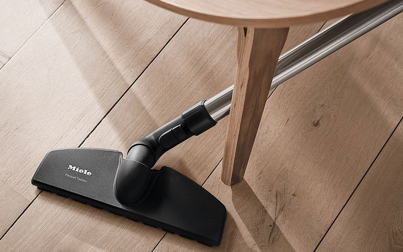 Miele stofzuiger met antistatische borstel op laminaatvloer voorkomt statische elektriciteit