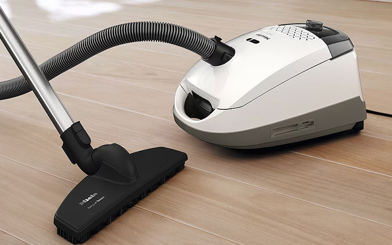 Traditionele stofzuiger met zak op houten vloer met hoog energieverbruik 1200-2400 watt