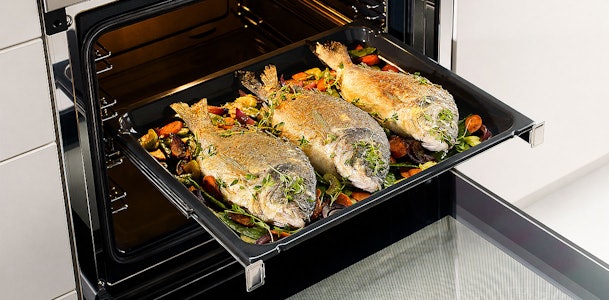 Vis met groenten op bakplaat als complete maaltijd in één keer klaargemaakt in de stoomoven