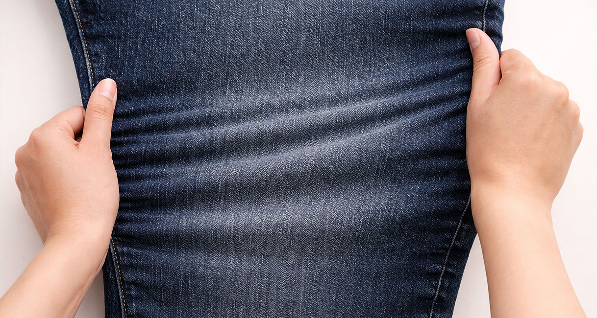 Handen rekken stretch jeans met focus op elasticiteit en gevoeligheid voor hitte