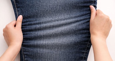 Handen rekken stretch jeans met focus op elasticiteit en gevoeligheid voor hitte