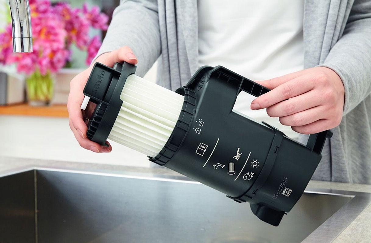 Handen reinigen Miele HEPA-filter voor stofzuiger zonder zak boven gootsteen