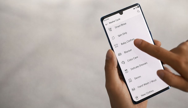 LG ThinQ app op smartphone met overzicht van downloadbare wasprogramma's zoals Baby Clothes en Delicate Dresses