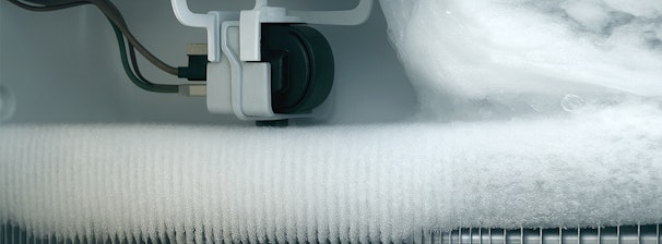 Ijsvorming rond onderdelen in een koelkast, met zichtbare leidingen en mechaniek.