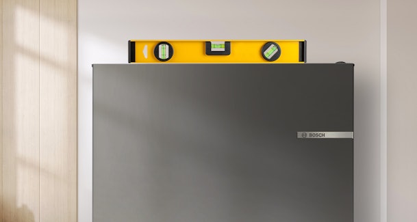 Waterpas ligt boven op een koelkast om te controleren of hij recht staat.