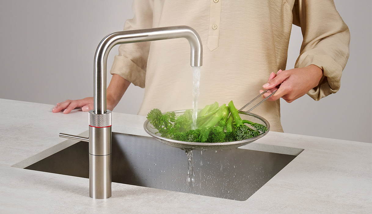 Vrouw blancheert broccoli onder kokend water uit Quooker Fusion Square kraan