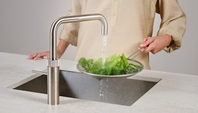 Vrouw blancheert broccoli onder kokend water uit Quooker Fusion Square kraan