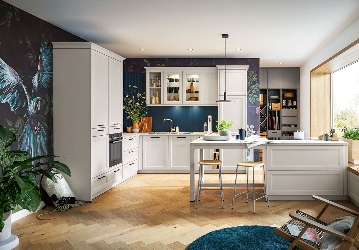 Lichte landelijke keuken met witte fronten, houten vloer en donkere accentwand met botanisch patroon.