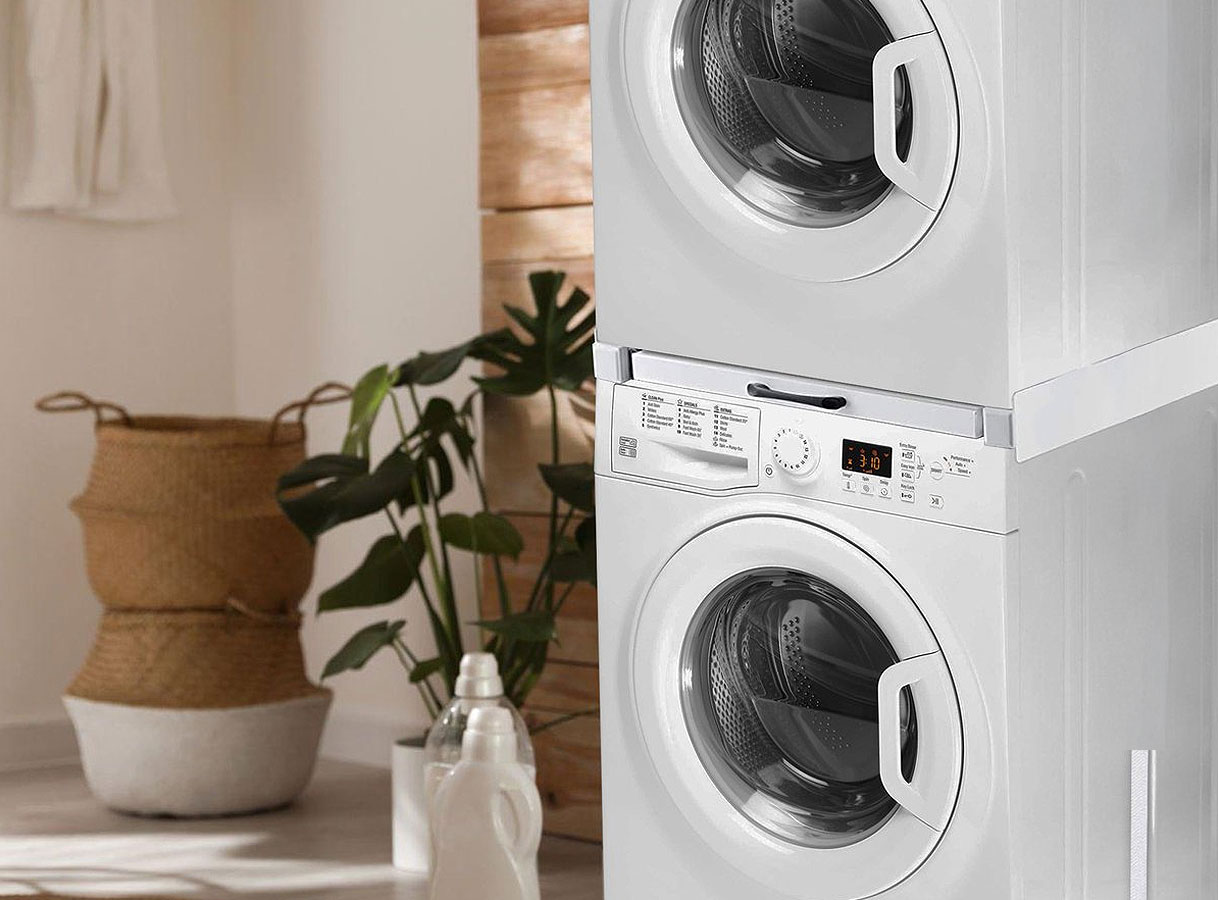 Gestapelde wasmachine en droger met tussenstuk in moderne wasruimte