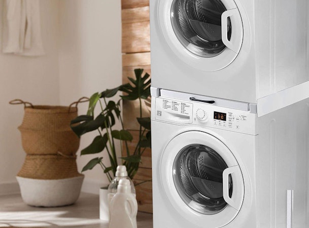 Gestapelde wasmachine en droger met tussenstuk in moderne wasruimte