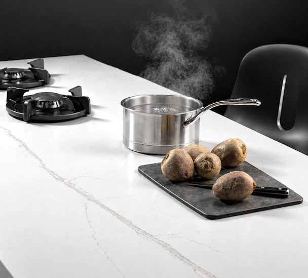 Keukenblad met dampende pan en aardappelen op snijplank naast gasbrander