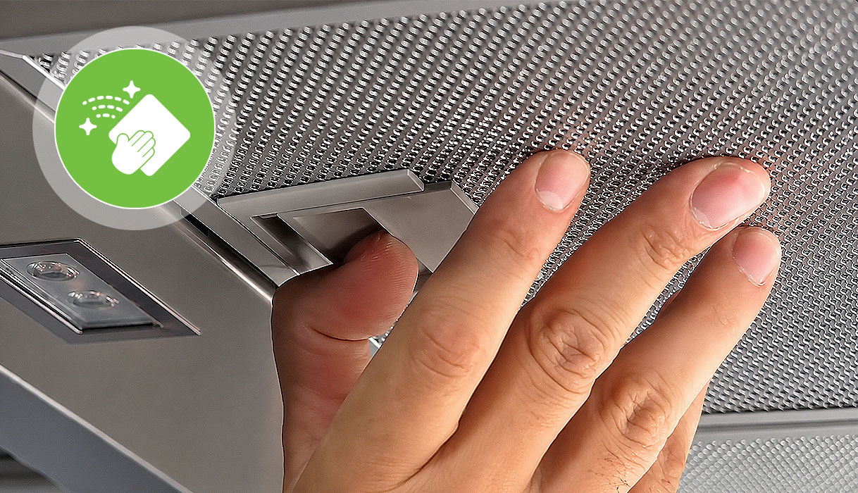 Hand klikt het vetfilter los van de afzuigkap om het schoon te maken