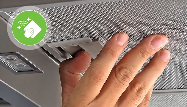 Hand klikt het vetfilter los van de afzuigkap om het schoon te maken