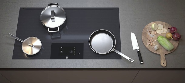 V-ZUG inductiekookplaat met pannen en ingrediënten op werkblad, Zwitsers design en innovatieve kooktechnologie