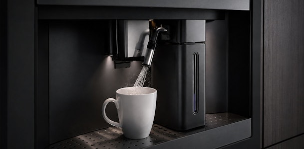 Heet water stroomt in een kop naast het waterreservoir van een V-ZUG koffiemachine