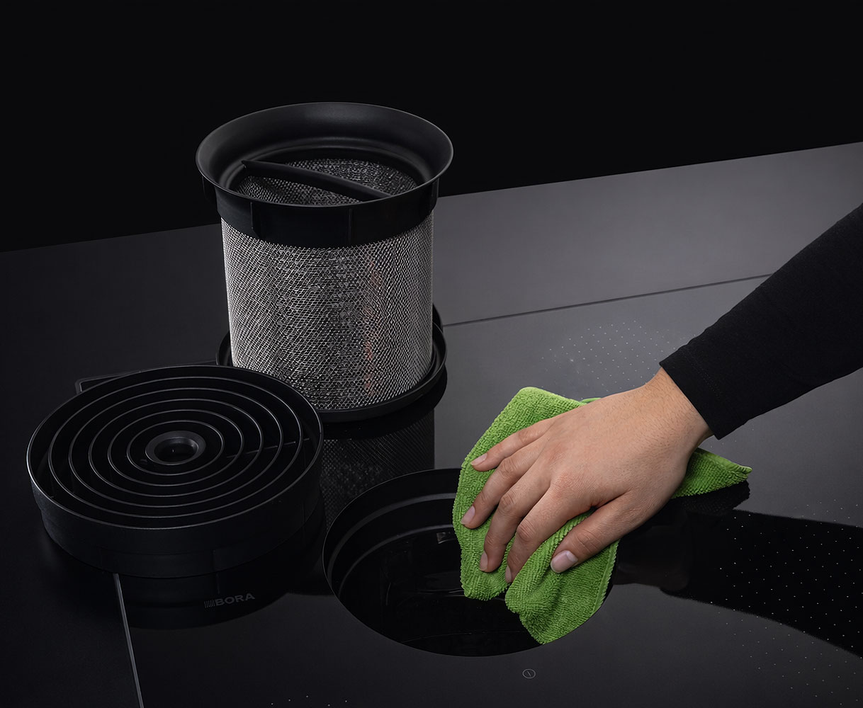 Hand reinigt kookplaat met geïntegreerde afzuiging en verwijderbaar vetfilter na het koken