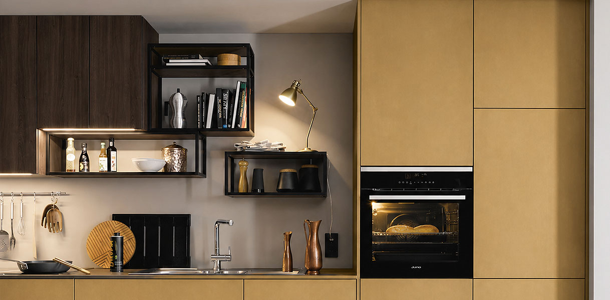 Keuken met hoge kast, inbouwoven, open plankjes met flessen en boeken en spoelbak met accessoires