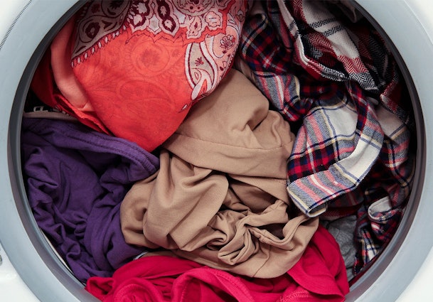 Overvolle wasmachine trommel met verschillende kleuren kleding door elkaar