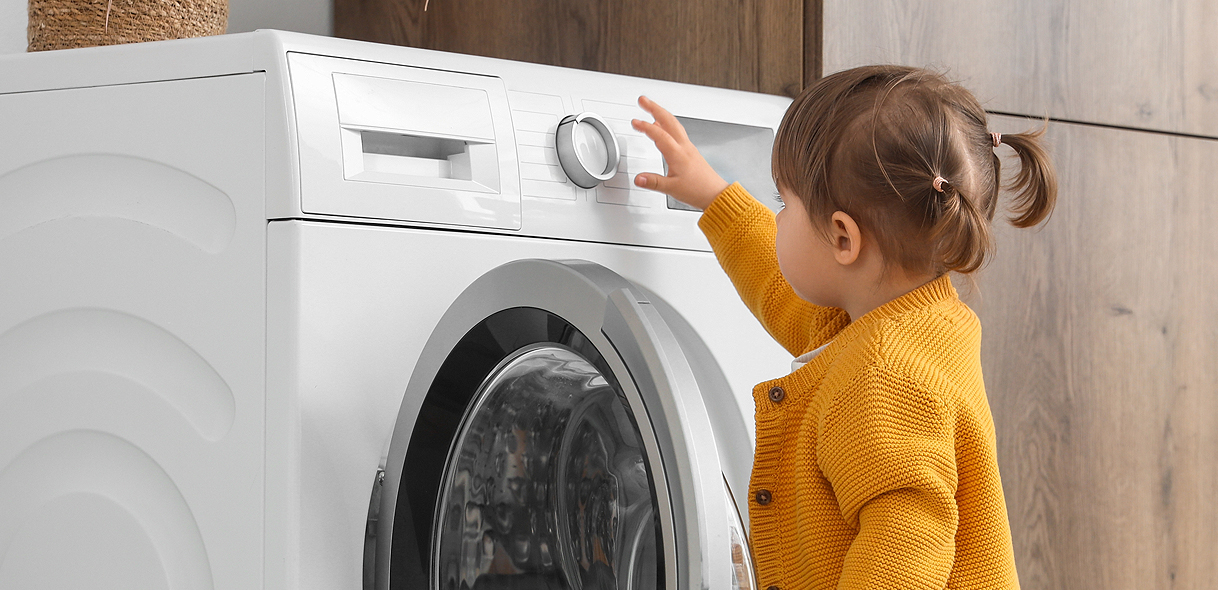 Peuter reikt naar bedieningspaneel van wasmachine