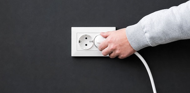 Hand haalt de stekker van de afzuigkap uit het stopcontact voor de veiligheid
