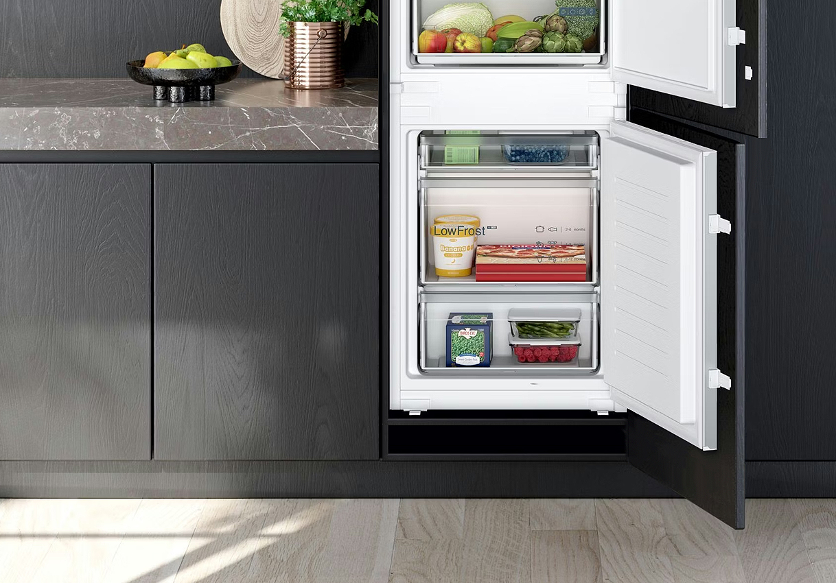 Inbouw koelkast met dubbele bodem voor gecontroleerde ventilatie onder het apparaat, geïntegreerd in een donkere keuken.