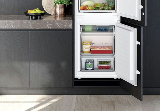 Inbouw koelkast met dubbele bodem voor gecontroleerde ventilatie onder het apparaat, geïntegreerd in een donkere keuken.