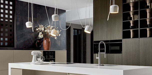 Design keuken met asymmetrische hanglampen en speelse verlichting boven kookeiland