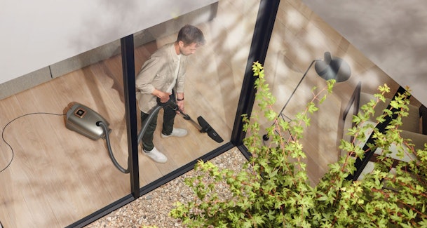 Man stofzuigt moderne woonkamer parketvloer verminderde zuigkracht probleem diagnostiek trap glazen wand