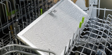 Metalen vetfilter van vlakscherm afzuigkap wordt schoongemaakt in de vaatwasser
