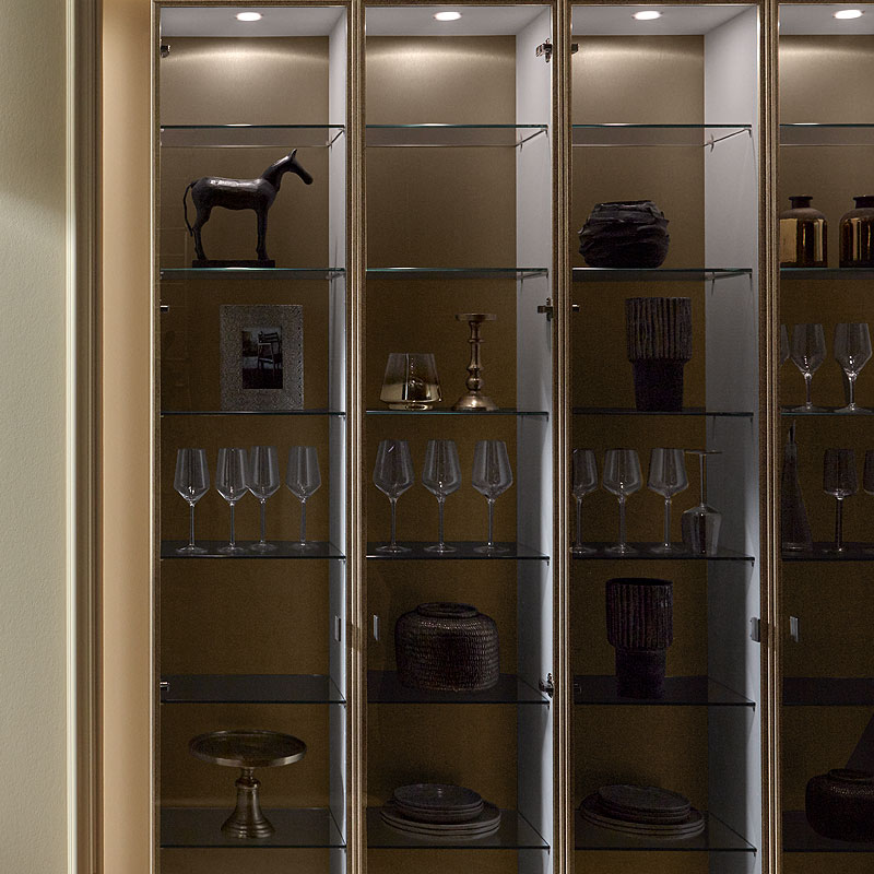 Vitrinekast Parsol grijs met bronzen omlijsting en verlichting.