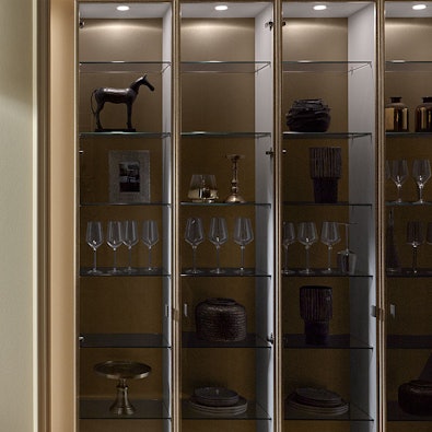 Vitrinekast Parsol grijs met bronzen omlijsting en verlichting.