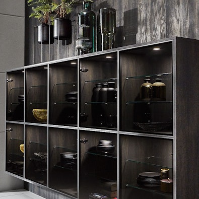 Zwevende vitrinekast in Parsol grijs met spots op blackwood wand.