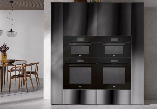 Miele VitroLine ovens met volledig glazen fronten in obsidiaanzwart, geïntegreerd in moderne keukenwand
