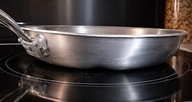 RVS pan op inductiekookplaat gezien van opzij om de vlakheid van de bodem te beoordelen