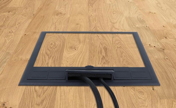 Vloerstopcontact met kabeldoorvoer in houten vloer naast kookeiland voor stroomvoorziening