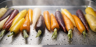 Kleurrijke wortels die worden gestoomd in een stoommandje voor gezonder koken met behoud van vitamines