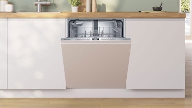 Volledig geïntegreerde vaatwasser open met zichtbare korven en besteklade in witte keuken