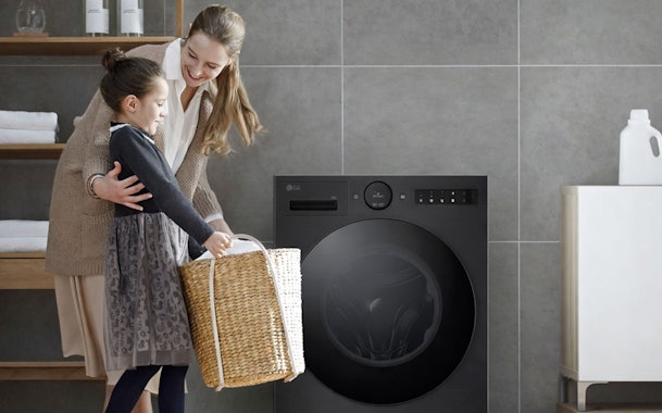 Moeder en dochter vouwen samen wasgoed naast een LG wasmachine in een lichte wasruimte
