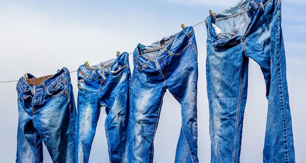 Jeans hangend aan waslijn met aandacht voor krimp pasvorm en kleurbehoud bij drogen