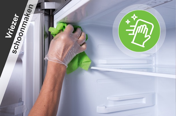 Hand reinigt binnenkant van een vriezer met een doek tijdens periodiek schoonmaken