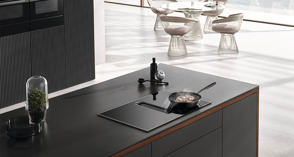 Moderne open keuken met kookplaat met geïntegreerde afzuiging op een kookeiland zonder afzuigkap voor maximale ontwerpvrijheid