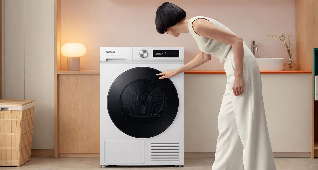 Vrouw laadt wasgoed in Samsung warmtepompdroger van 9 kg in een moderne wasruimte