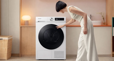 Vrouw laadt wasgoed in Samsung warmtepompdroger van 9 kg in een moderne wasruimte