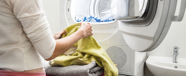 Persoon haalt was uit een warmtepompdroger om de juiste trommelcapaciteit en vulgewicht te illustreren