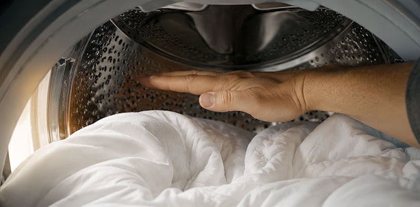Hand toont een handbreedte ruimte boven het wasgoed in de trommel van een wasmachine