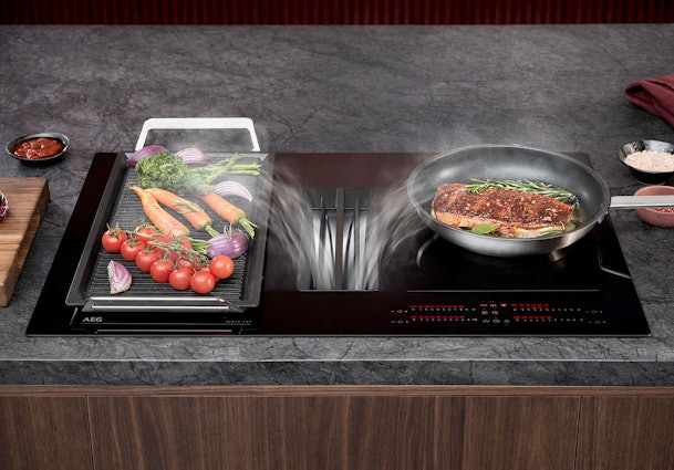 AEG inductiekookplaat met geïntegreerde afzuiging en pannen met groenten op het kookoppervlak