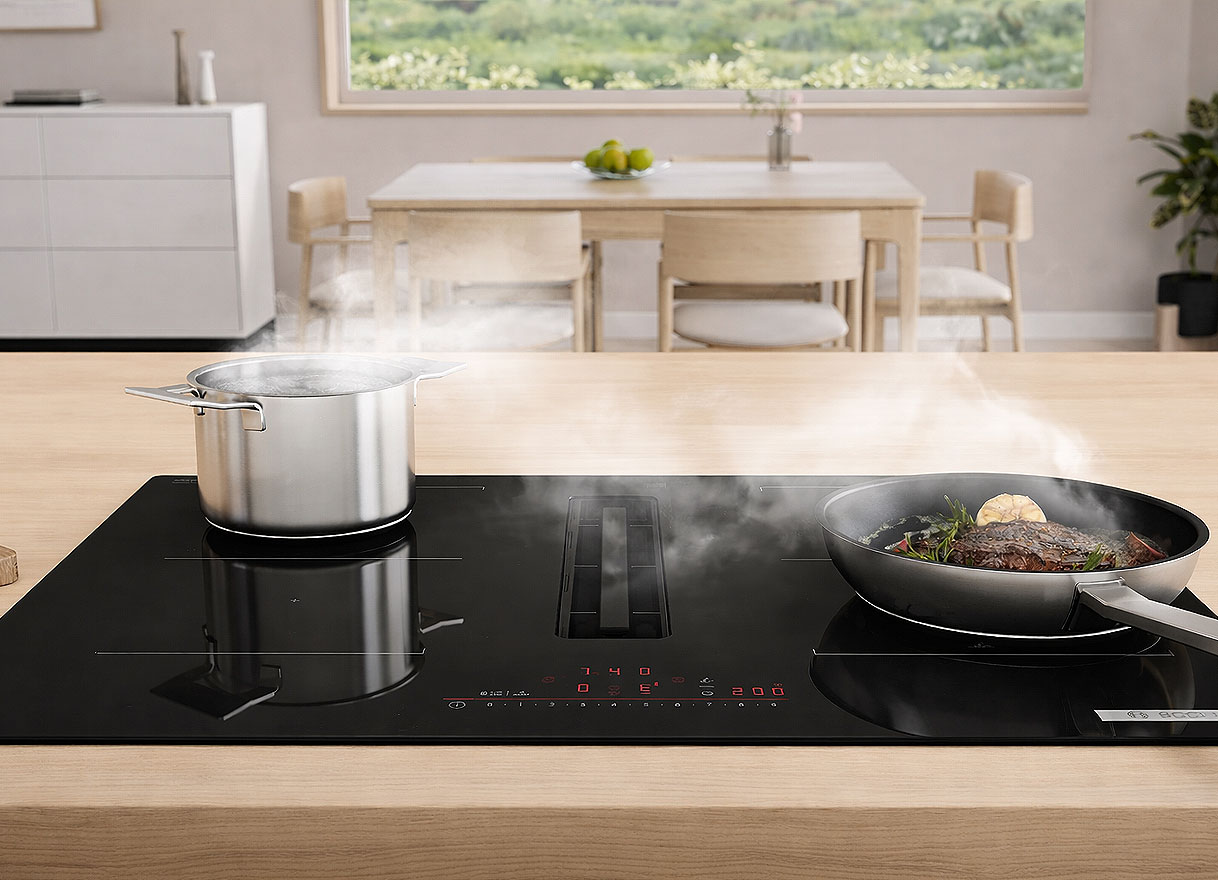 Bosch inductiekookplaat met geïntegreerde afzuiging en pannen op het kookoppervlak in een moderne keuken