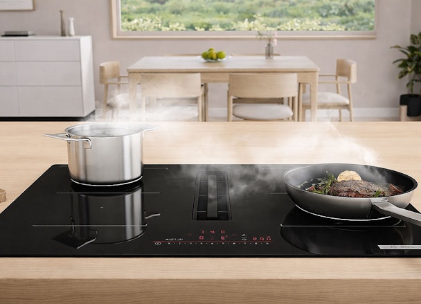 Bosch inductiekookplaat met geïntegreerde afzuiging en pannen op het kookoppervlak in een moderne keuken