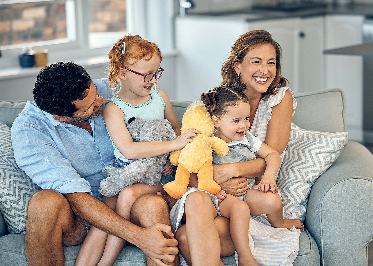 Gelukkig gezin met twee jonge kinderen op de bank als voorbeeld van een groot huishouden
