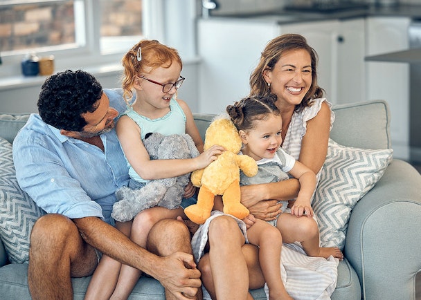 Gelukkig gezin met twee jonge kinderen op de bank als voorbeeld van een groot huishouden